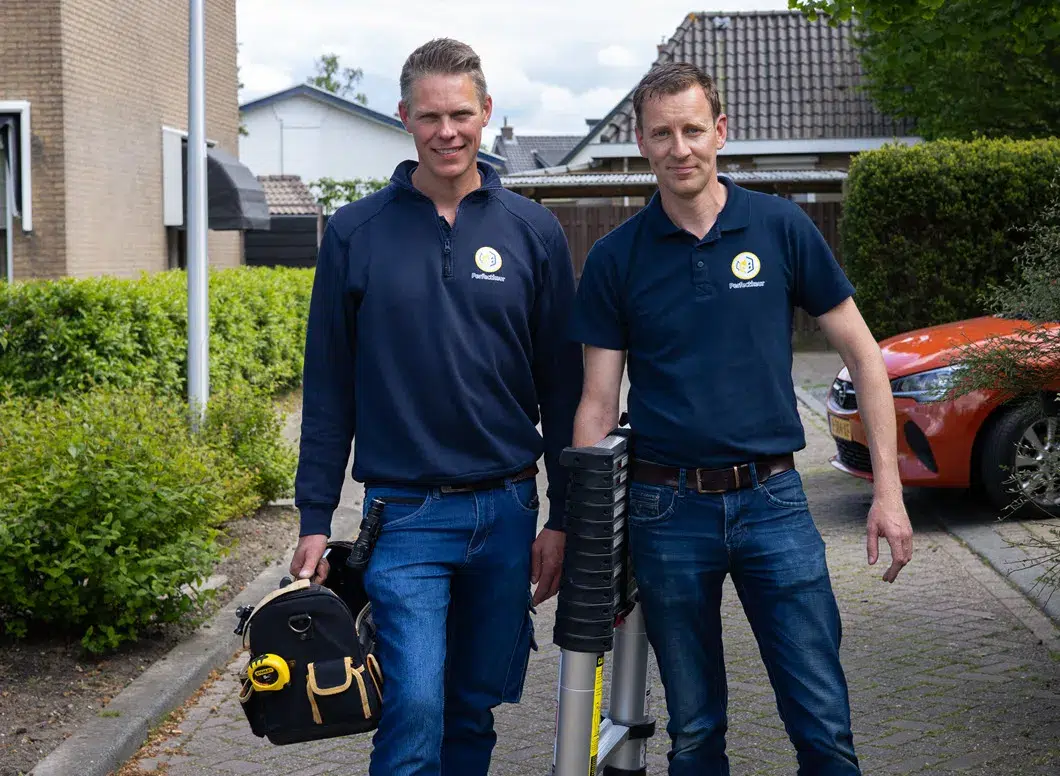 bouwkundige inspecteert binnenmuur met laserafstandsmeter in lege woonkamer met meetapparatuur op de vloer